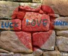 Czerwone serca malowane na kamiennym murem z tekstu "luck love health"