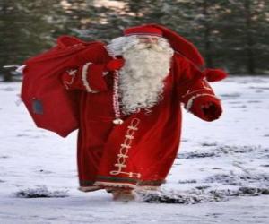 Układanka Santa Claus prowadzenia wielki worek na prezenty świąteczne w lesie